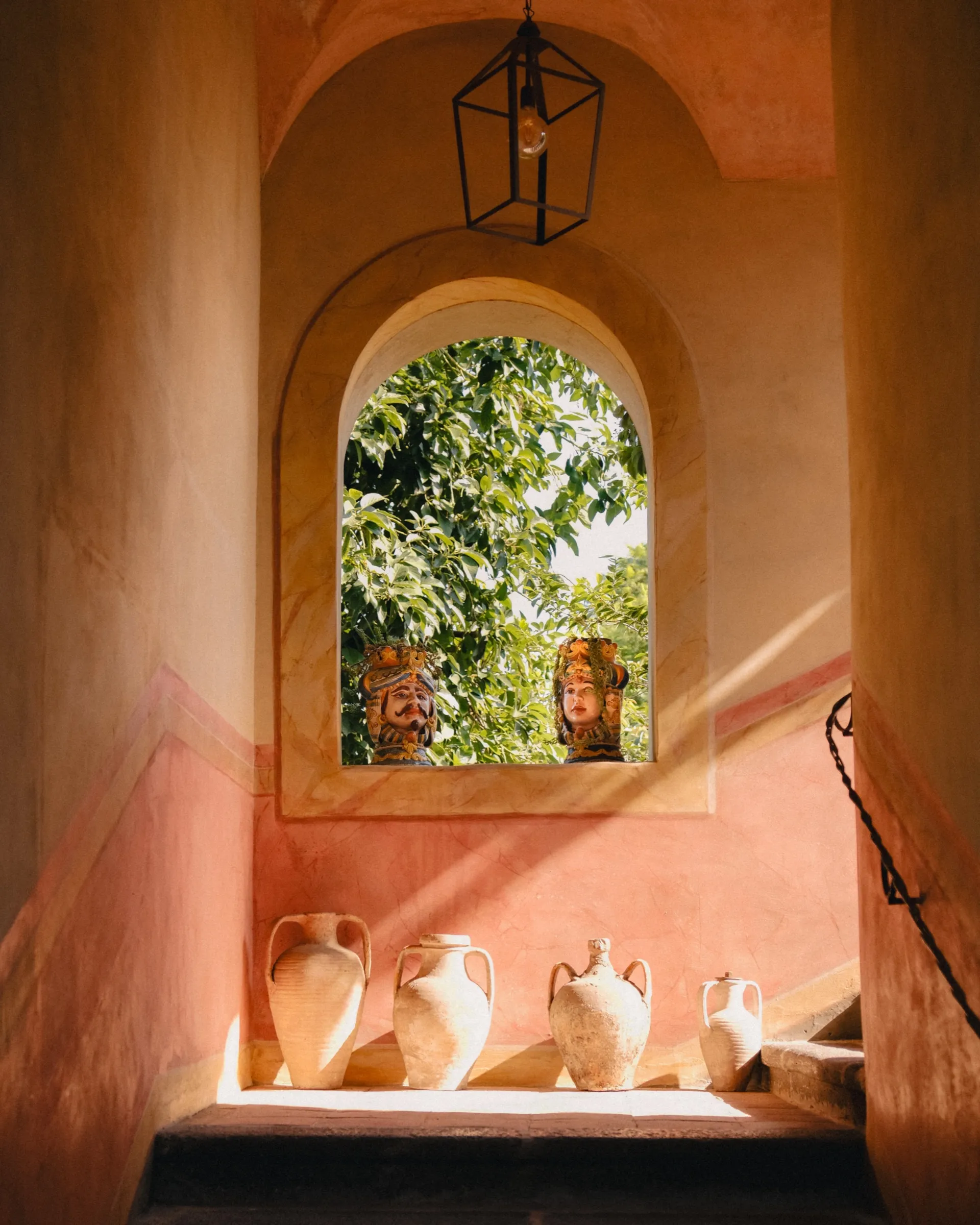 Nis met terracotta kruiken en een raam met uitzicht op groen