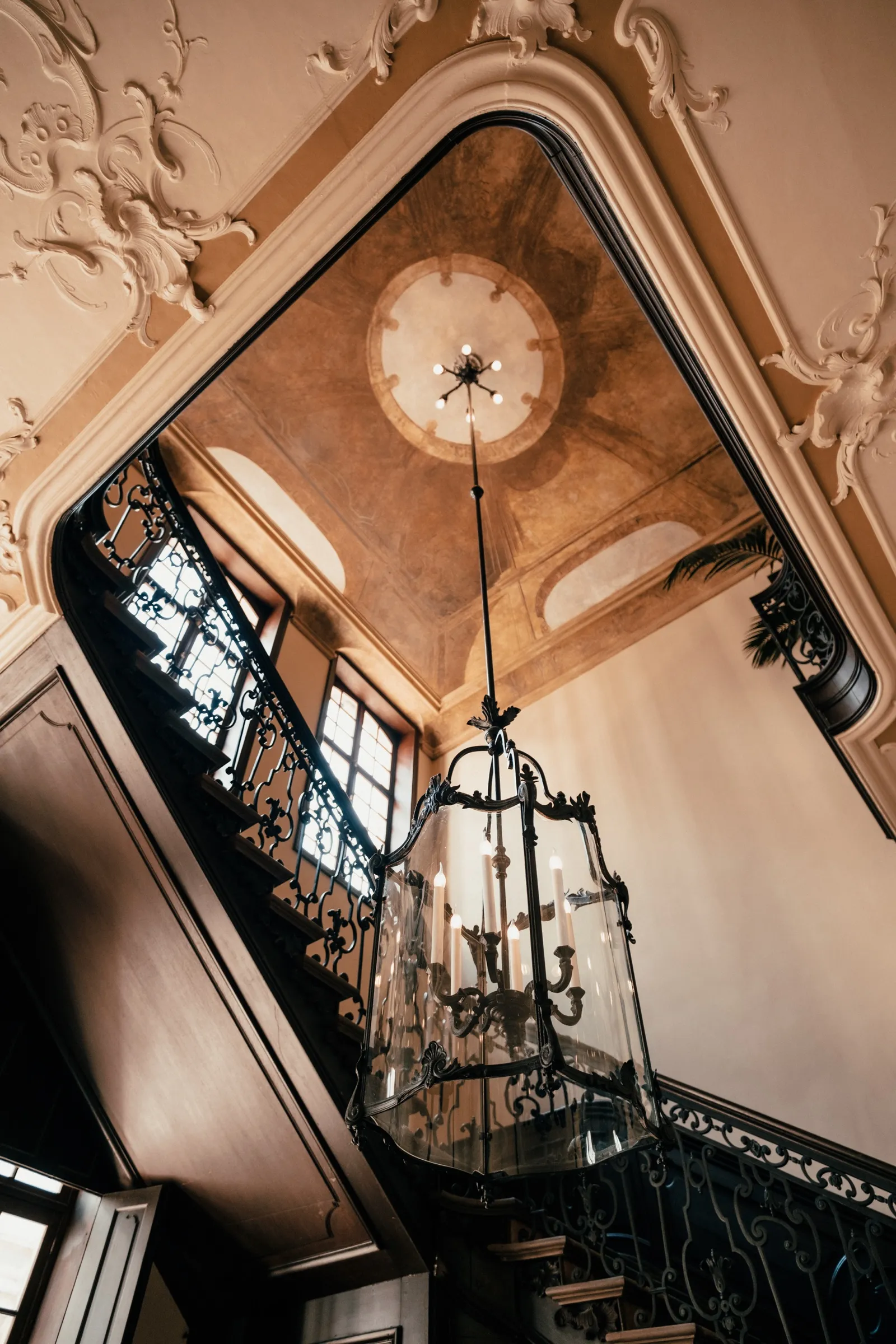 Rijk versierd plafond met stucwerk en een kroonluchter, van onderaf