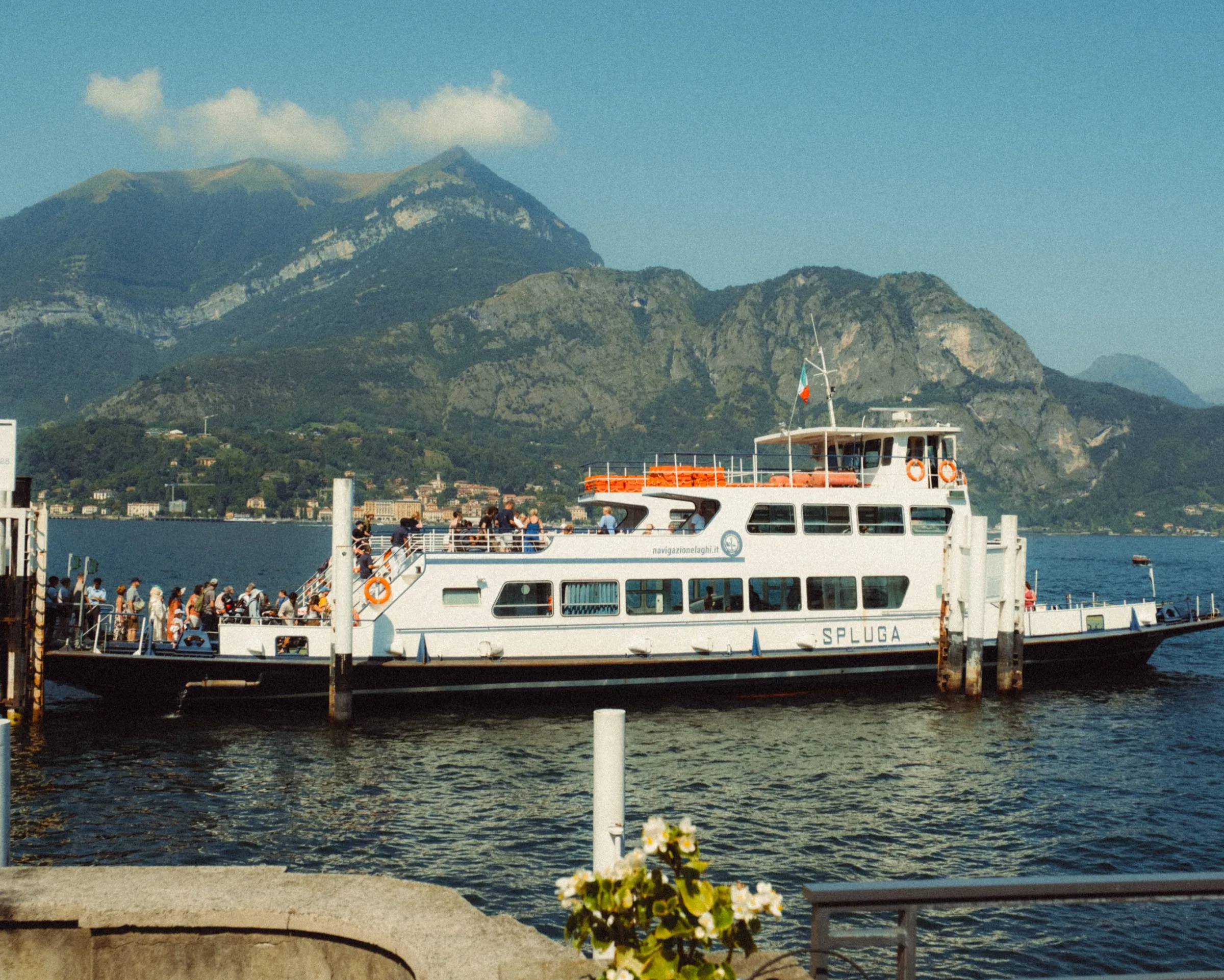 Veerboot aan de steiger met de bergen van het meer erachter