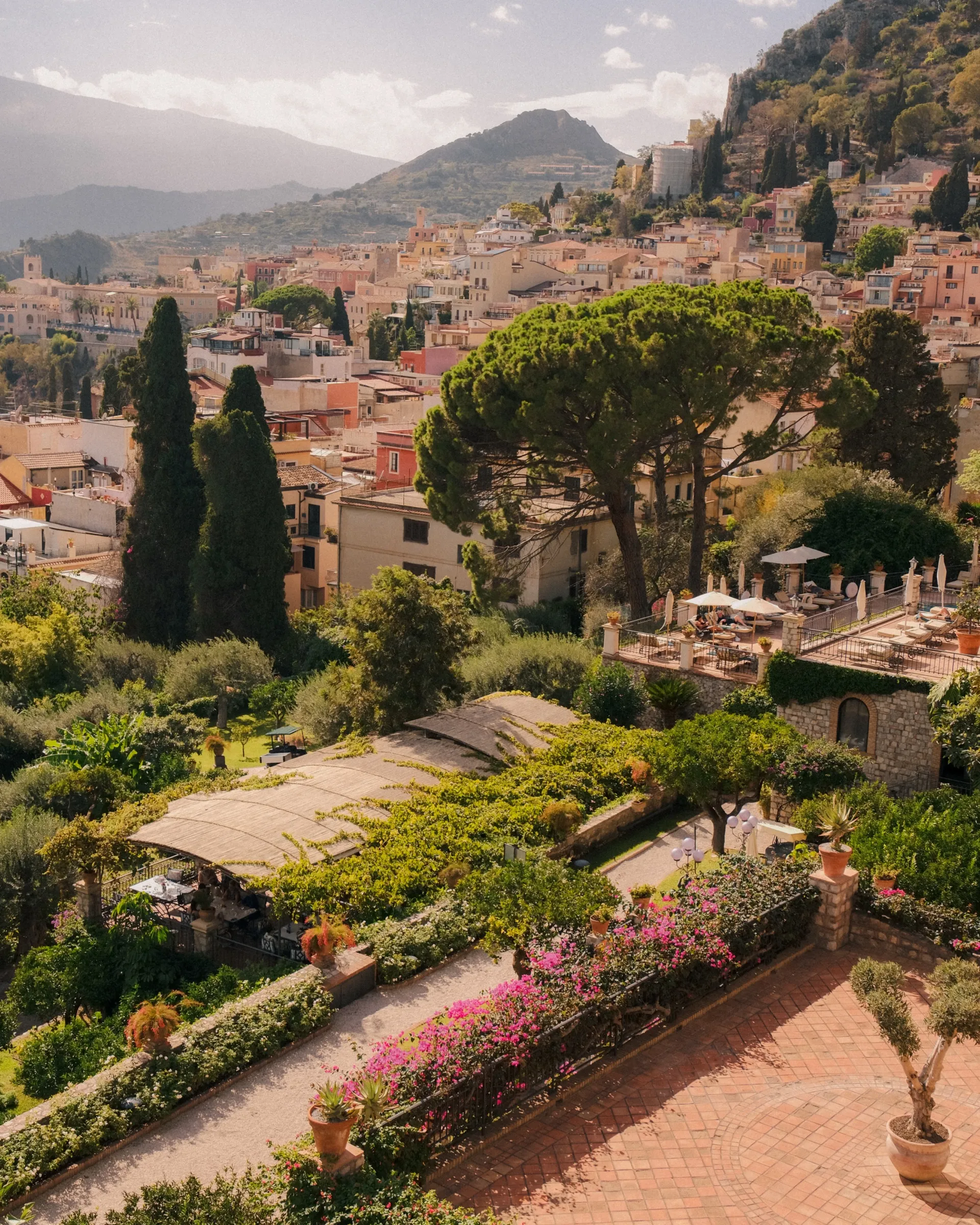 Uitzicht over Taormina met parasoldennen en een tuin op de voorgrond