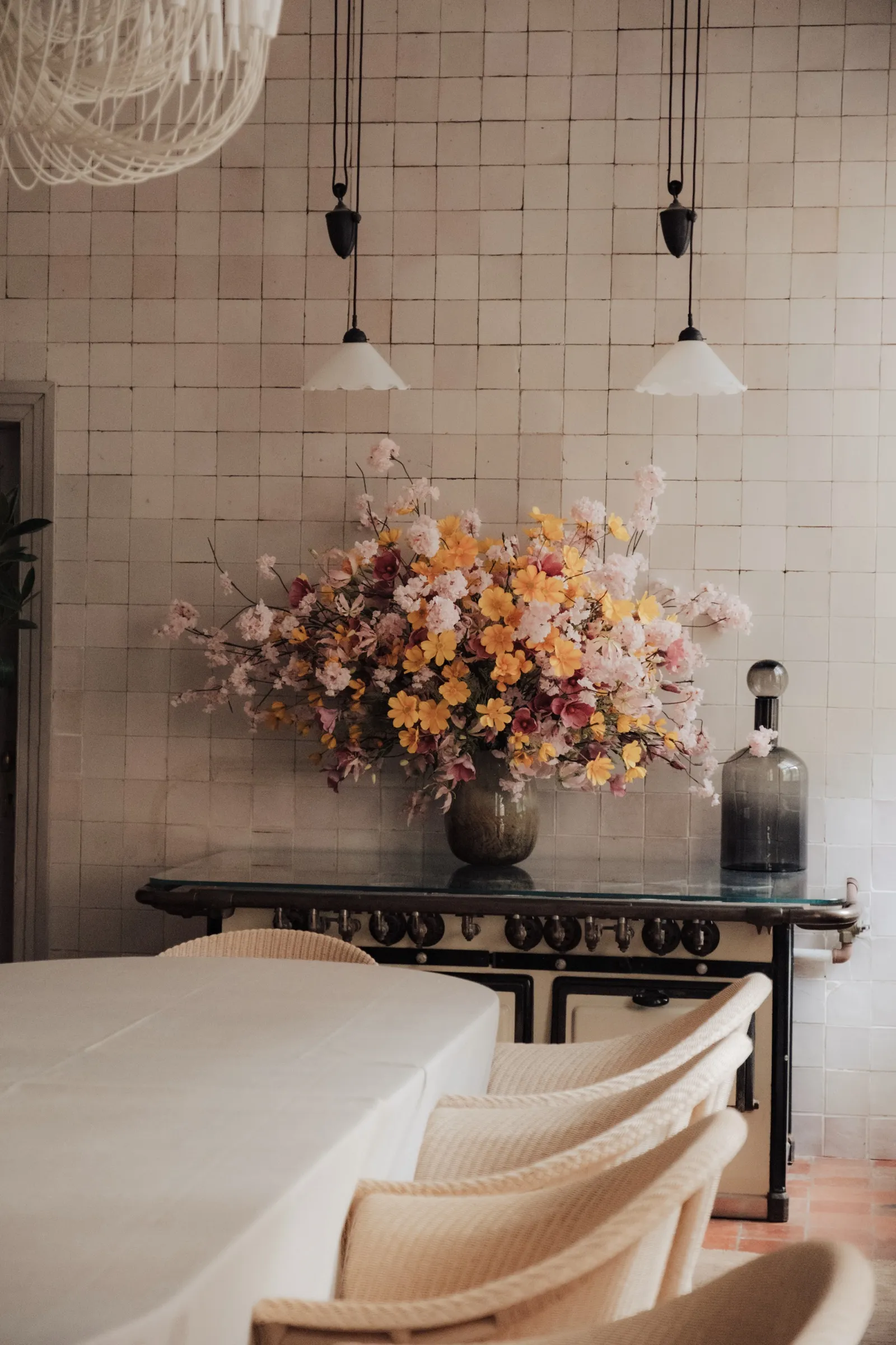 Groot bloemstuk op een donkere tafel tegen een witbetegelde muur