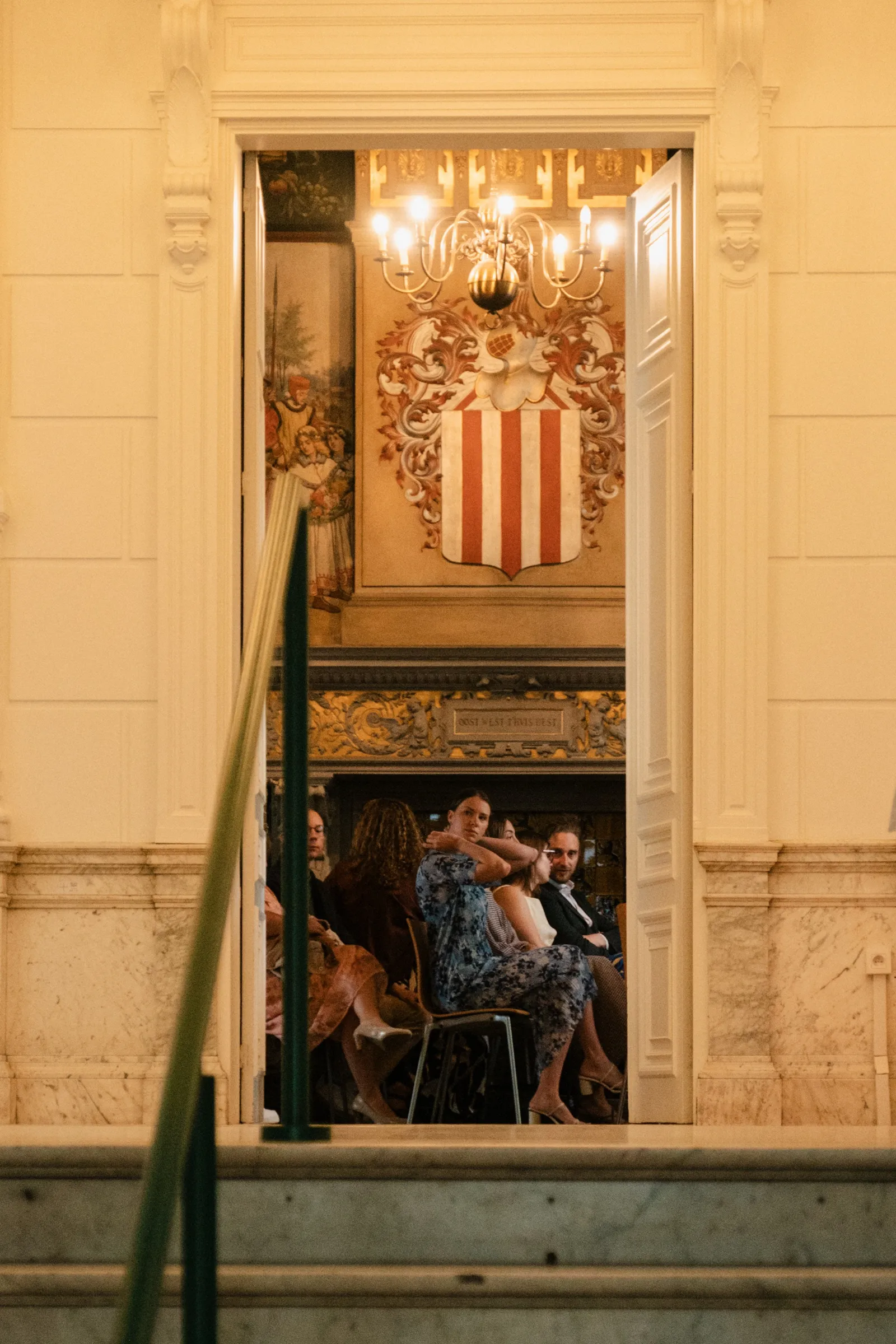 Deuropening naar de ceremoniezaal met een kroonluchter en wapenschild