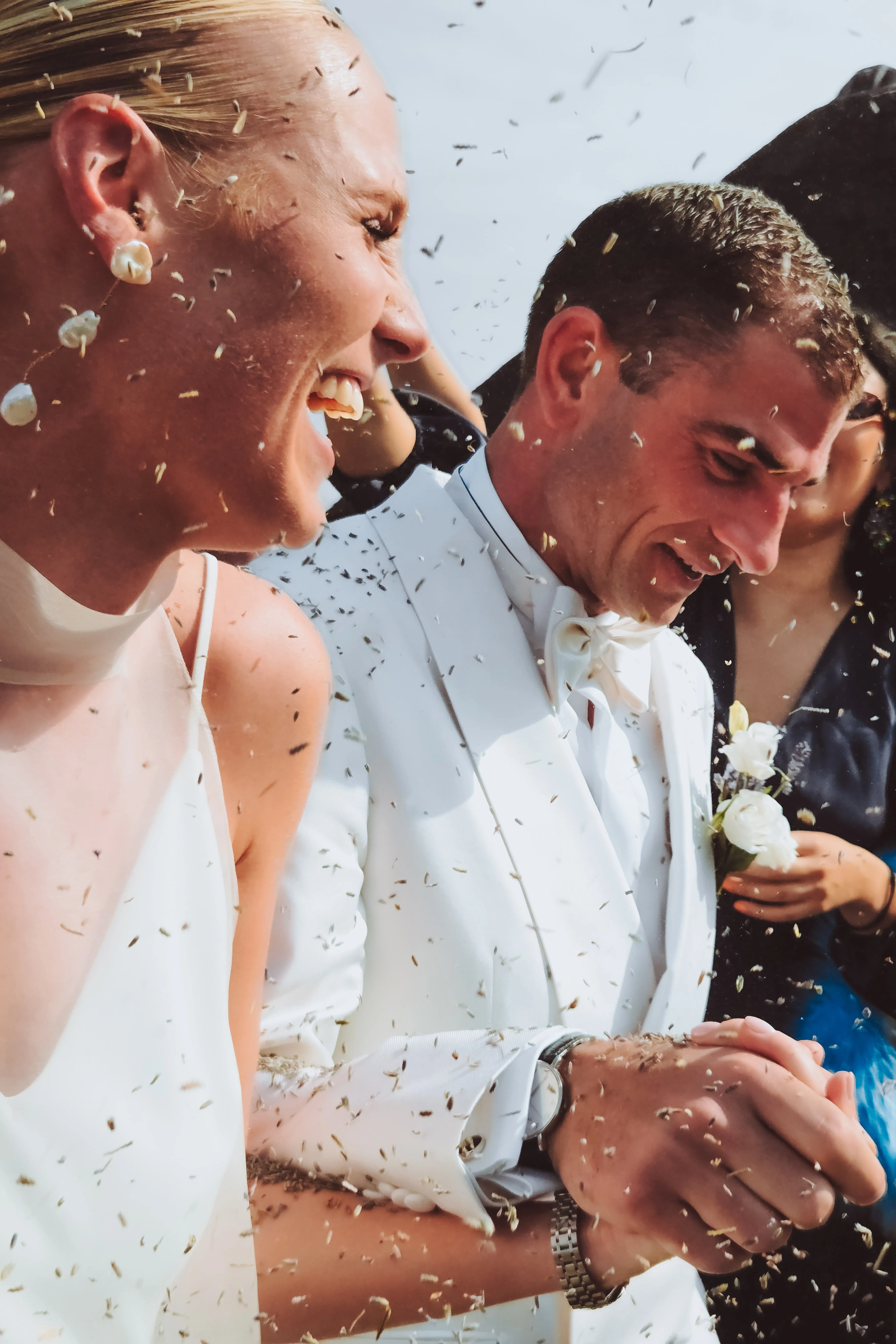Het bruidspaar lacht onder een regen van confetti