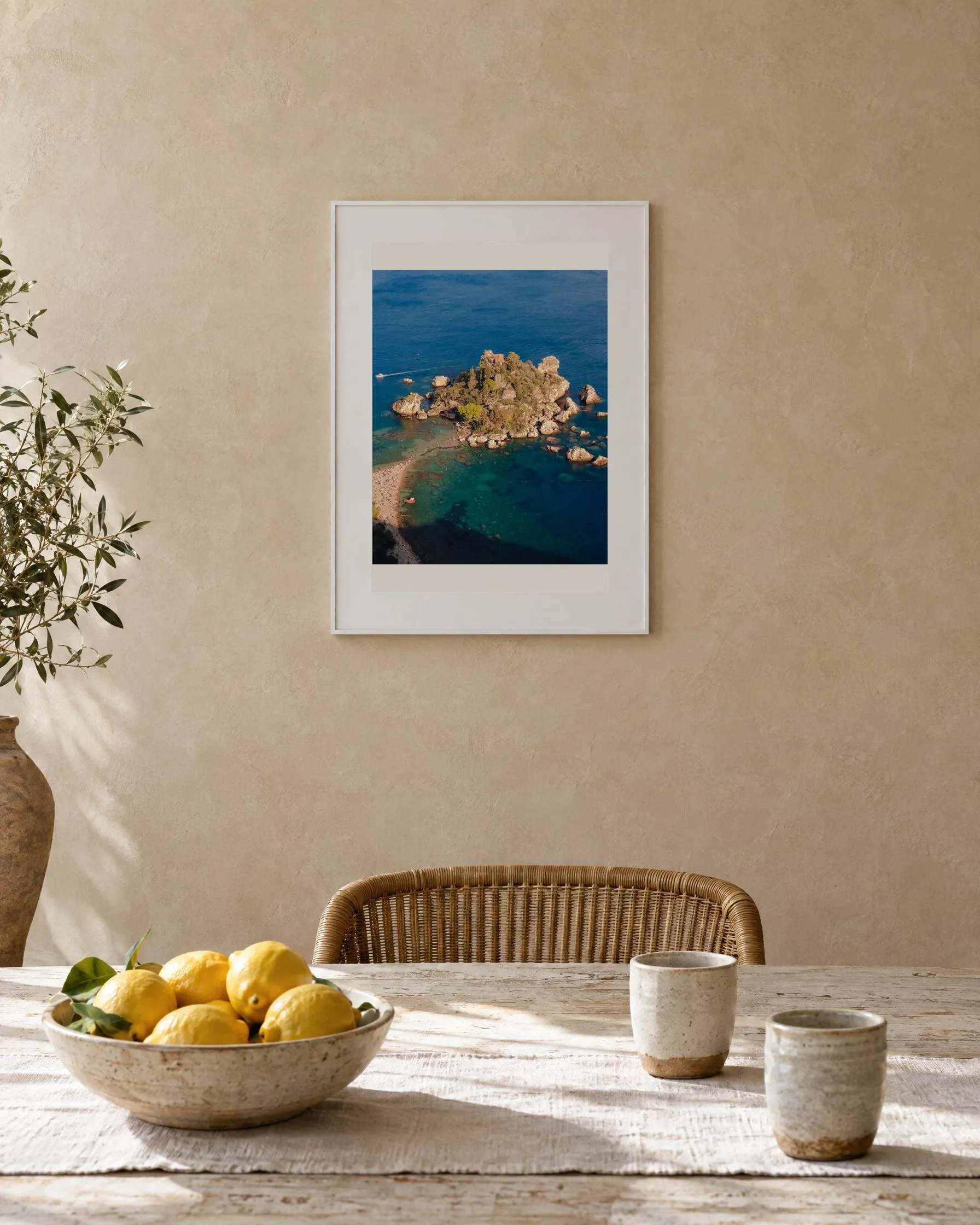 De print La Isola Bella in een witte lijst boven een eettafel met citroenen