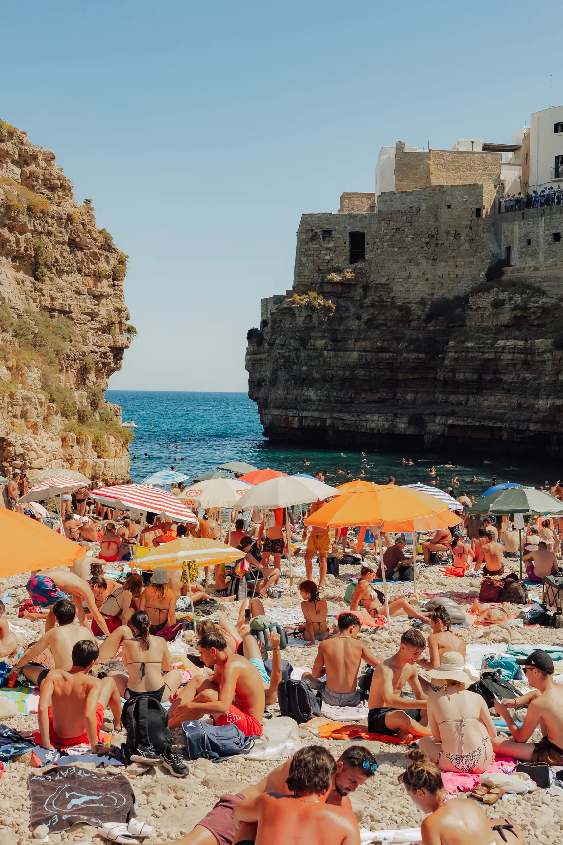 Het drukke strand van Polignano a Mare tussen de kliffen