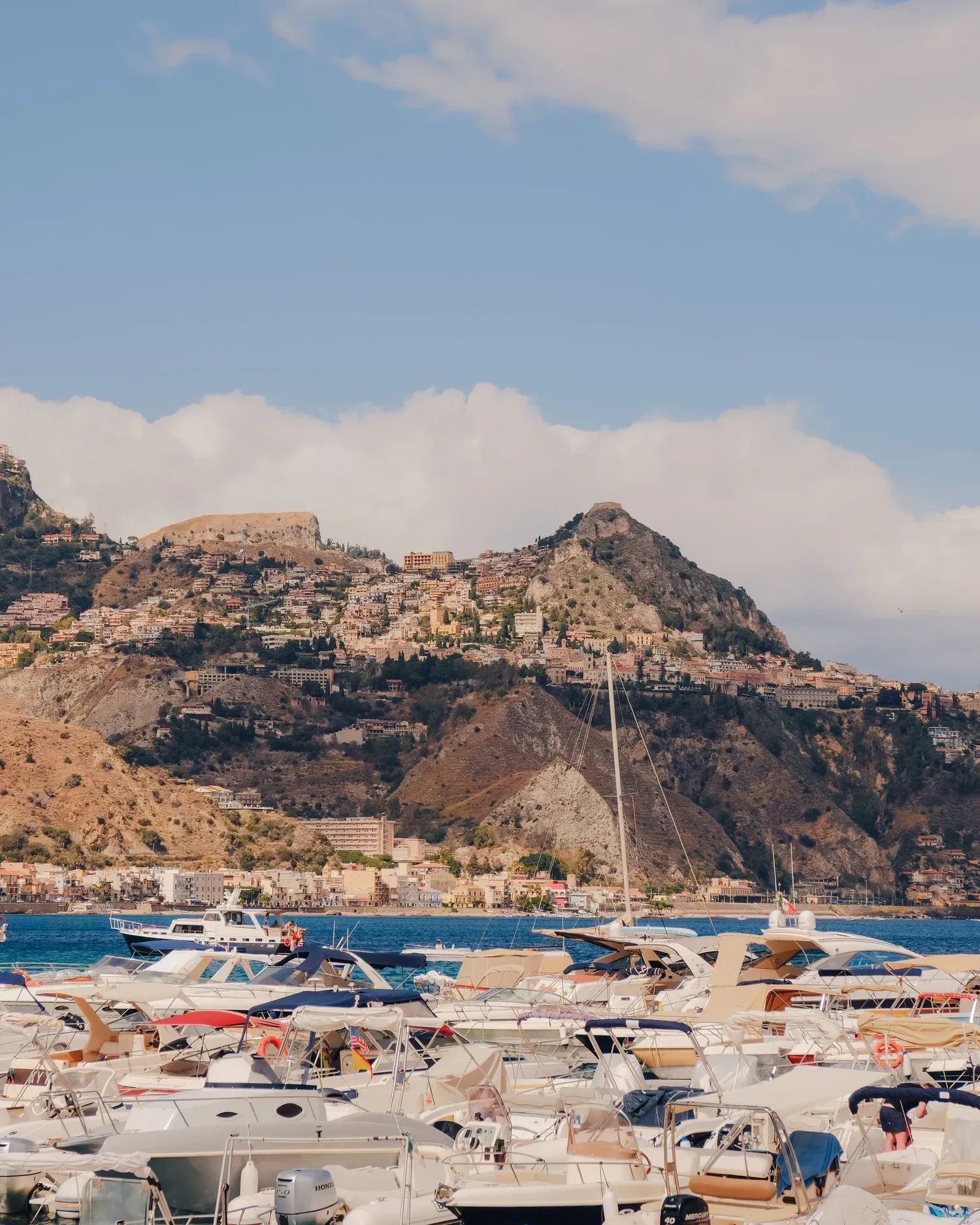 De haven van Taormina met boten en bergen